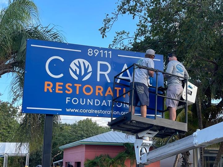 Two of our crew in the bucket installing the Coral Restoration Foundation pole sign