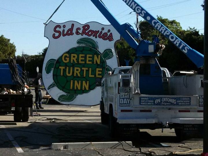 Eye Catchers Signs bucket truck lifting the Sid and Roxie's Green Turtle Inn sign into place