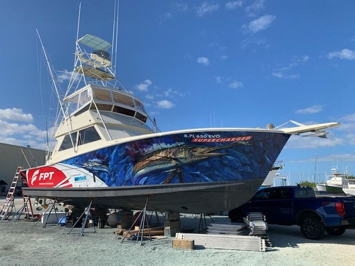 Sportfisher on stands with an FPT wrap: a marlin chasing bait through deep blue water along the hull