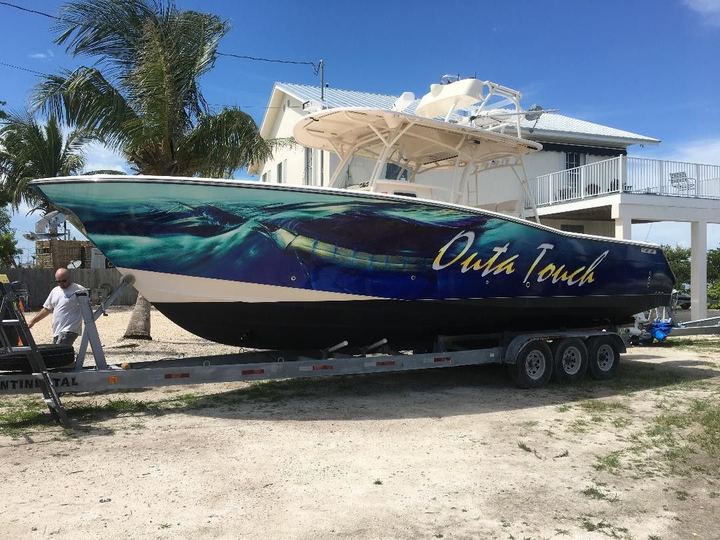 Boat on a trailer with an ocean wrap lettered Outa Touch