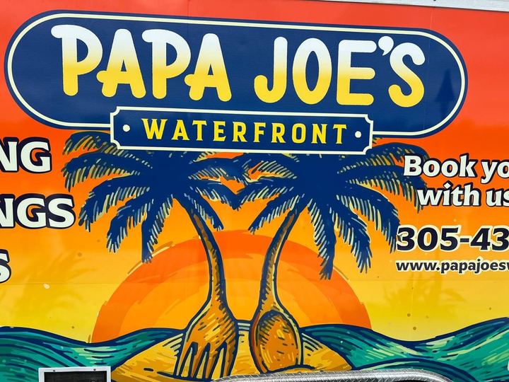 Close up of the Papa Joe's Waterfront trailer wrap with palm trees and a sunset