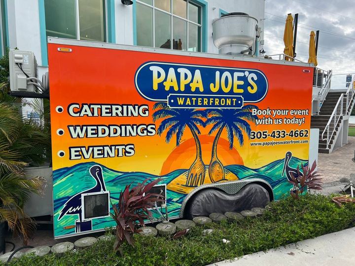 Papa Joe's Waterfront food trailer wrapped with palm trees, a sunset and catering, weddings and events