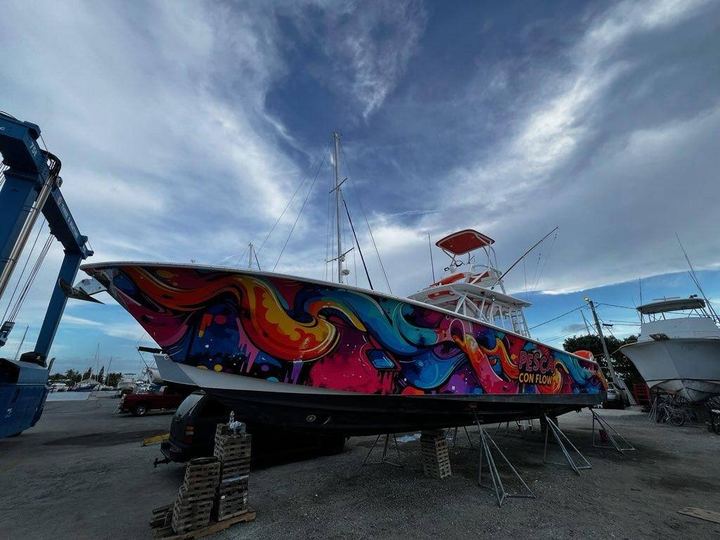 Pesca Con Flow sportfisher on stands in the yard with its full color wrap