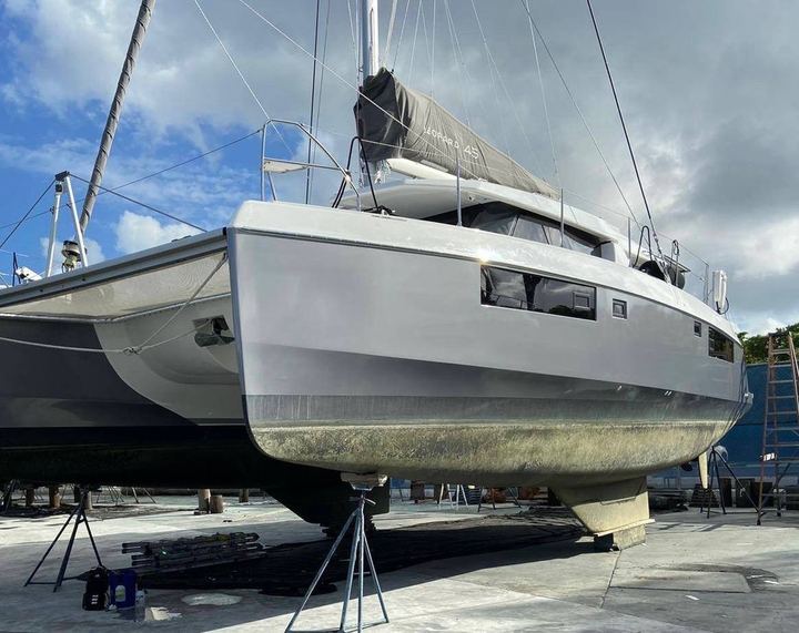 Sailing catamaran on stands in the yard with a silver hull wrap