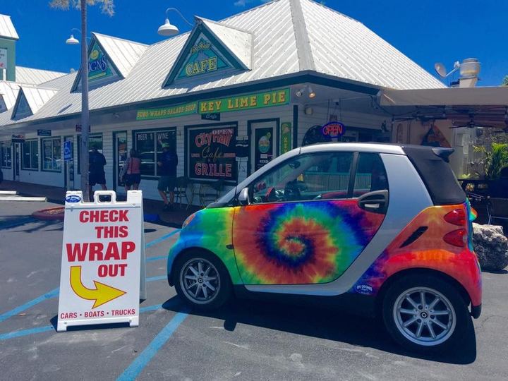 Small car with a rainbow tie-dye wrap