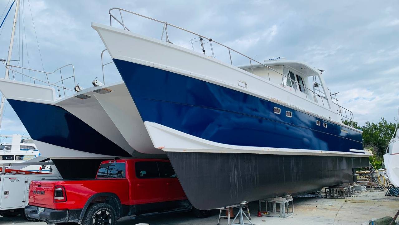 Large power catamaran on stands with a deep blue hull wrap