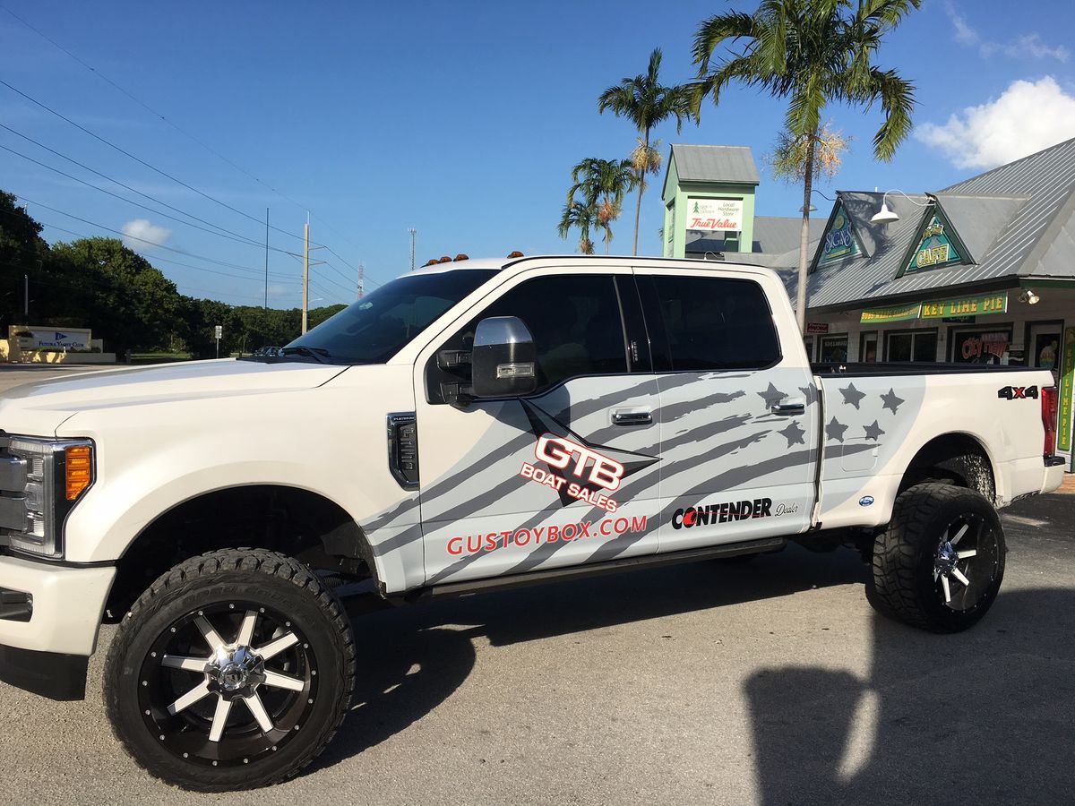 White pickup truck wrapped with a gray flag graphic and GTB Boat Sales lettering