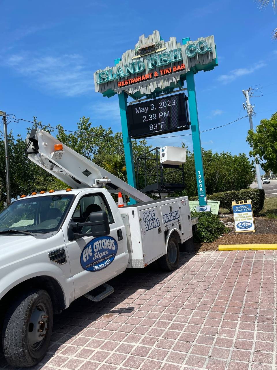 Island Fish Co. Restaurant and Tiki Bar pole sign with an LED message board, our bucket truck below