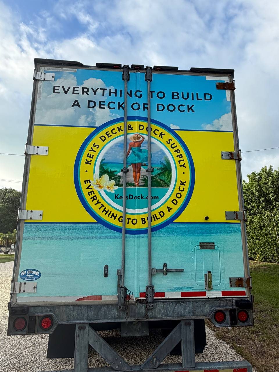 Rear doors of the Keys Deck & Dock Supply semi trailer with the logo and a beach dock scene