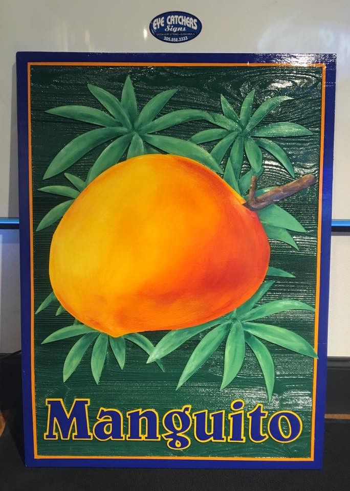 Carved Manguito sign with a painted mango and palm leaves