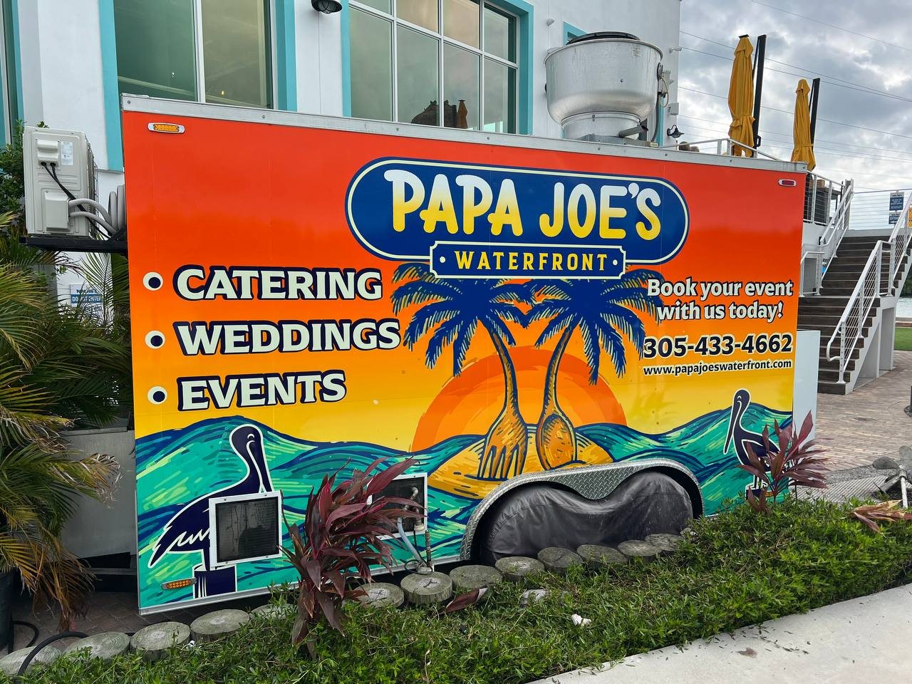 Papa Joe's Waterfront food trailer wrapped with palm trees, a sunset and catering, weddings and events