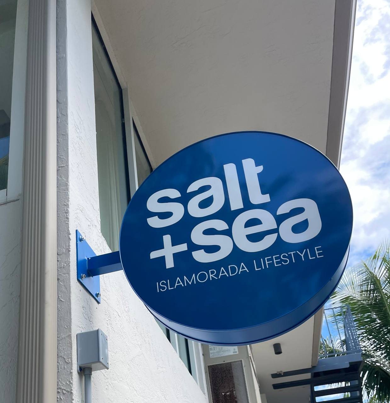 Round blue Salt + Sea Islamorada Lifestyle projecting sign on a bracket